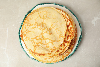Photo of Stack of fresh thin pancakes on light grey marble table, top view