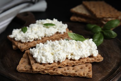 Photo of Crispy crackers with cottage cheese and basil on board, closeup