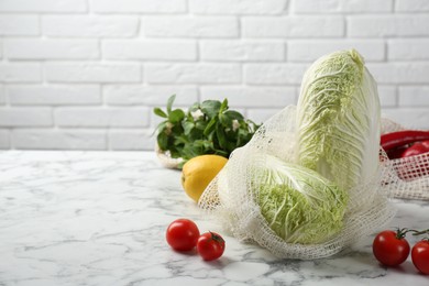 Fresh Chinese cabbages and other vegetables on white marble table near brick wall. Space for text