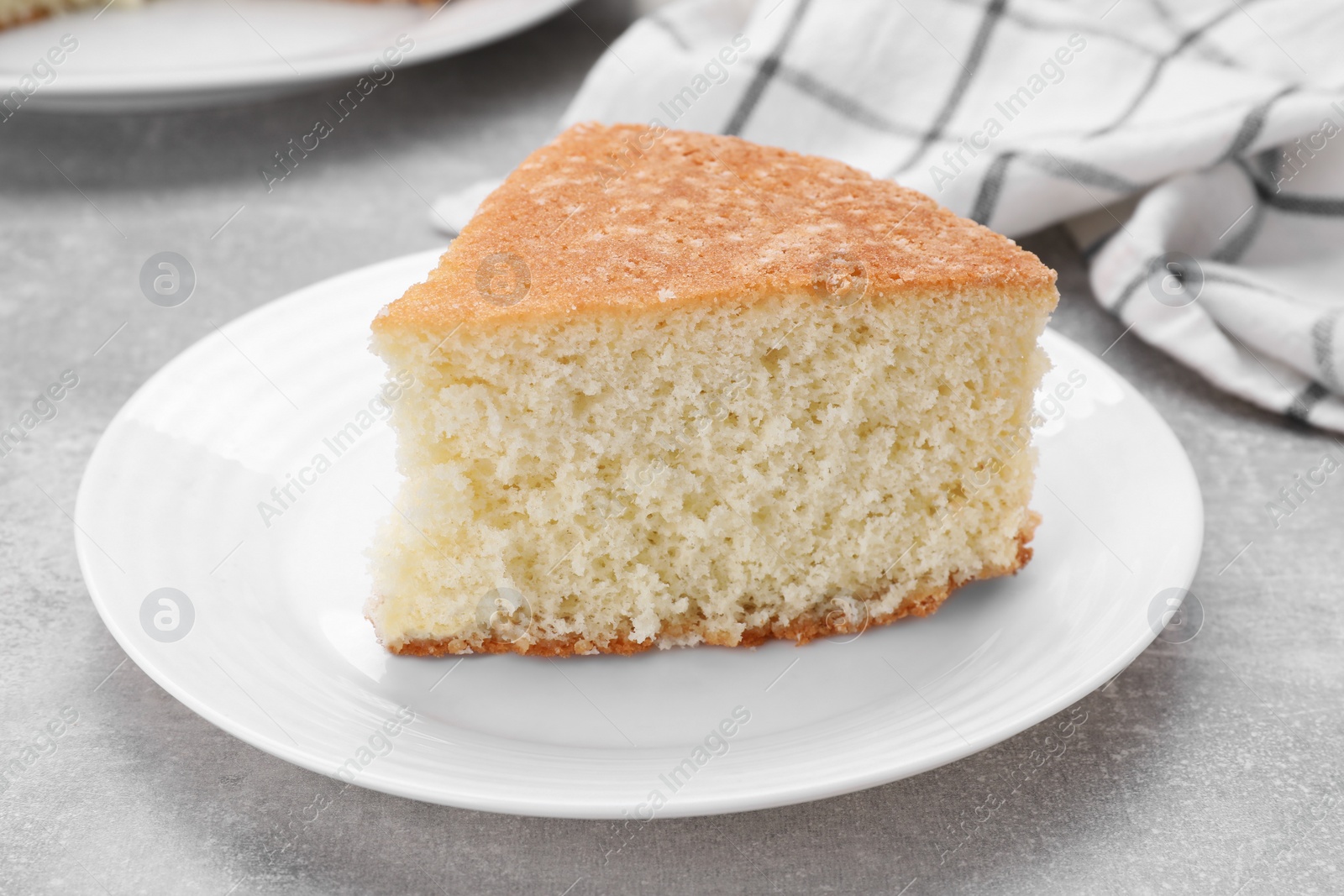 Photo of Piece of tasty sponge cake on grey table, closeup