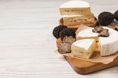 Photo of Soft cheese and fresh truffles on white wooden table, space for text