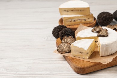 Soft cheese and fresh truffles on white wooden table, space for text