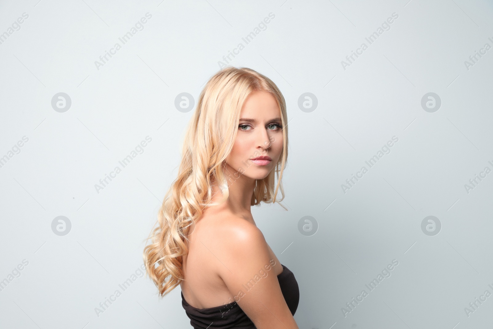 Photo of Beautiful woman with healthy long blonde hair on light background