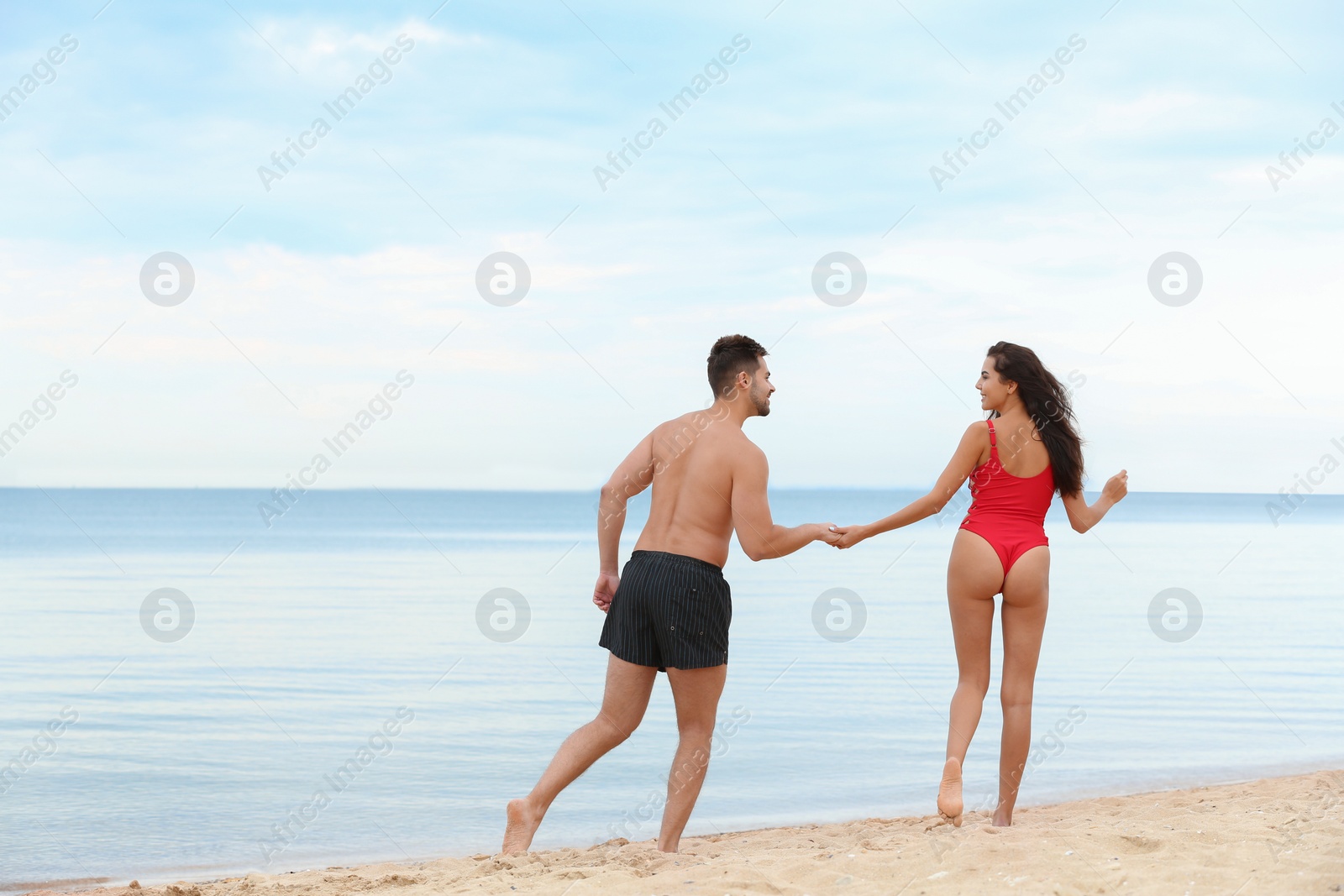 Photo of Happy young couple spending time together on beach near sea