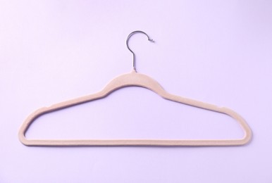 Photo of One beige hanger on violet background, top view