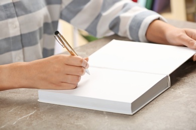 Photo of Writer signing autograph in book at table, closeup