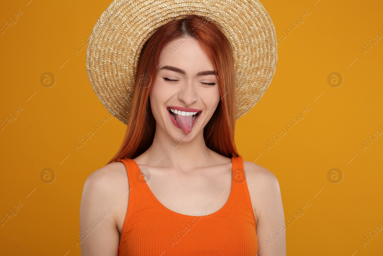 Photo of Happy woman showing her tongue on orange background