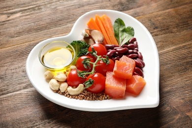Photo of Plate with products for heart-healthy diet on wooden table