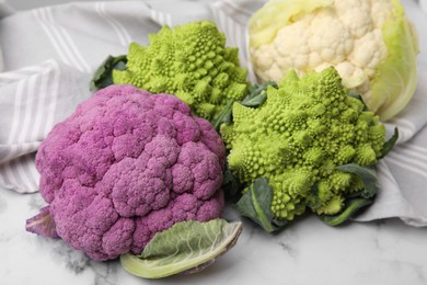 Different fresh cabbages on white marble table, closeup