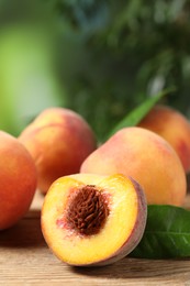 Photo of Cut and whole fresh ripe peaches on wooden table against blurred background, closeup. Space for text