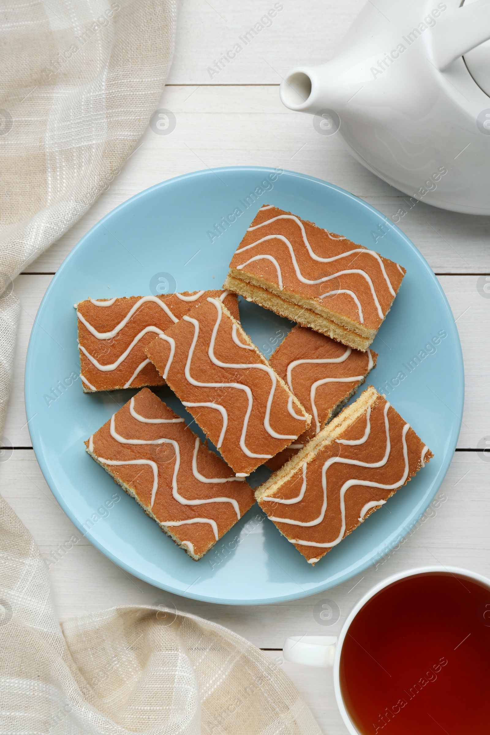 Photo of Tasty sponge cakes and hot drink on while wooden table, flat lay