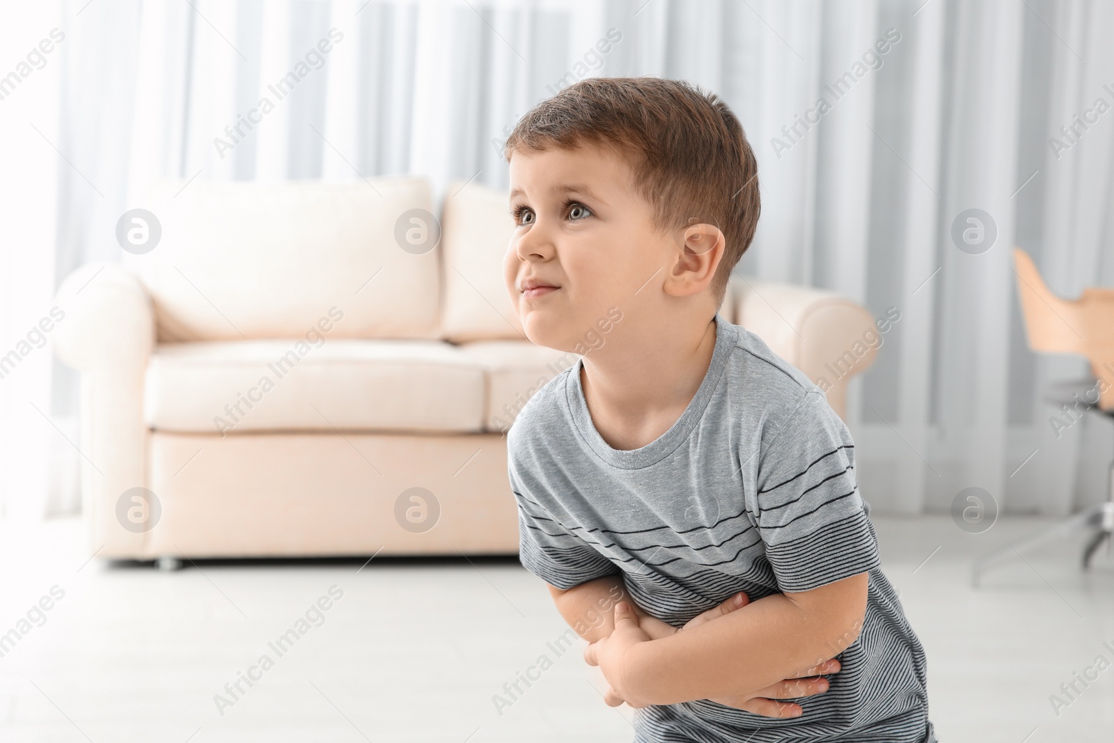Photo of Little boy suffering from nausea in living room