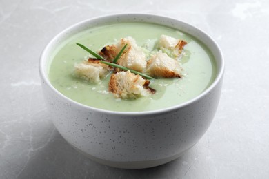 Photo of Bowl of delicious asparagus soup on light grey table