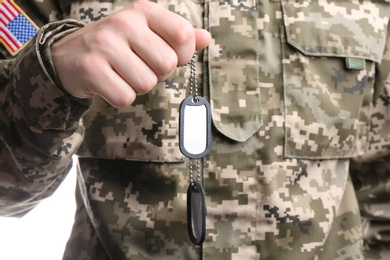 Photo of Man in camouflage uniform holding military ID tags, closeup