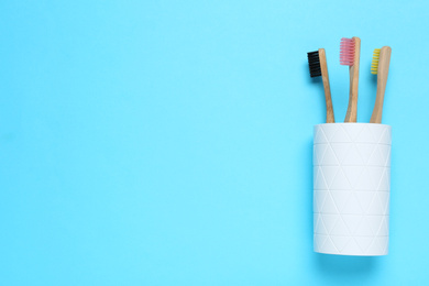 Toothbrushes in holder on light blue background, top view. Space for text