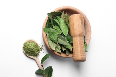 Wooden mortar and pestle with bay leaves on white background, top view