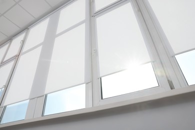 Photo of Large window with white roller blinds indoors, low angle view