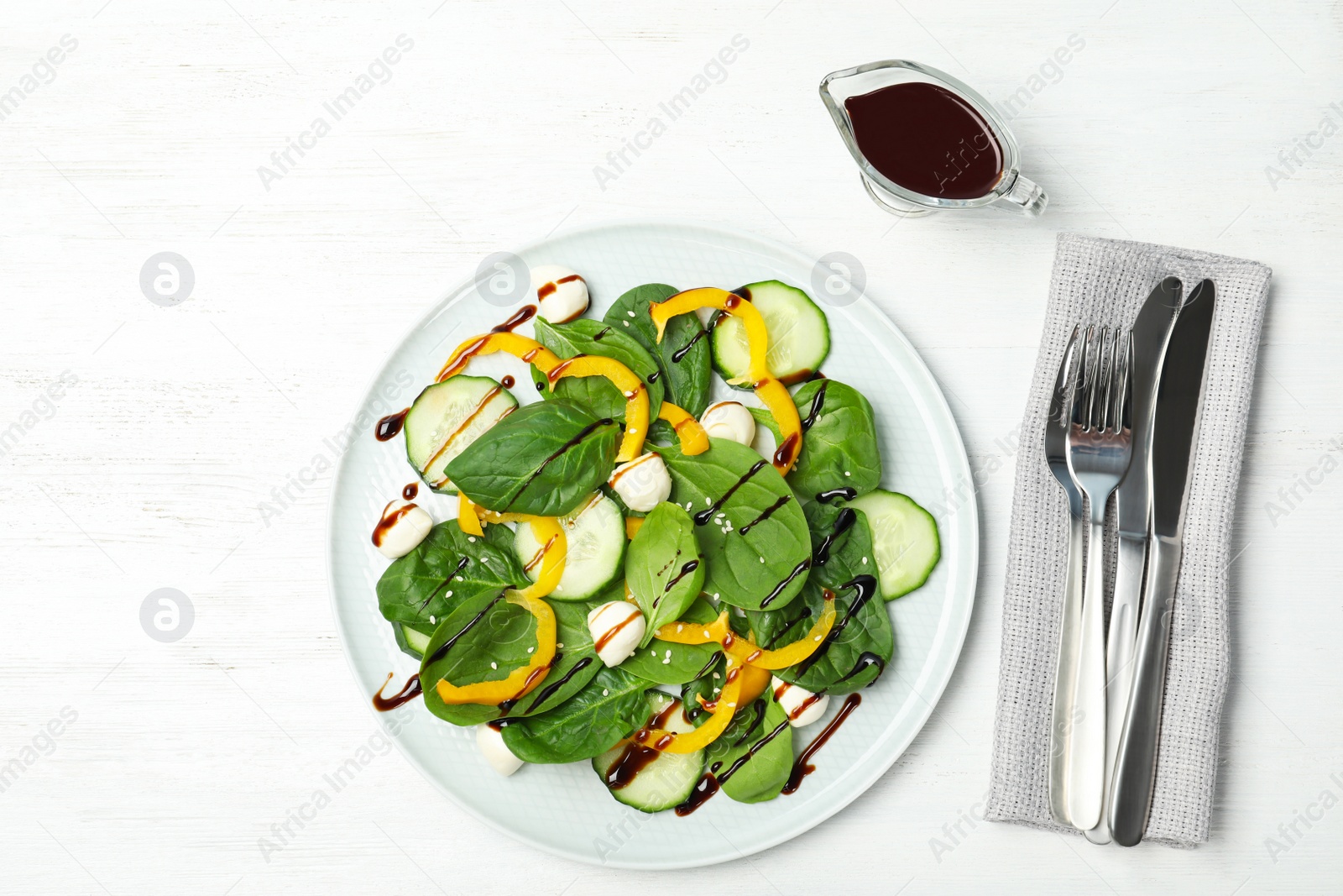 Photo of Fresh vegetable salad and balsamic vinegar served on white wooden table, top view