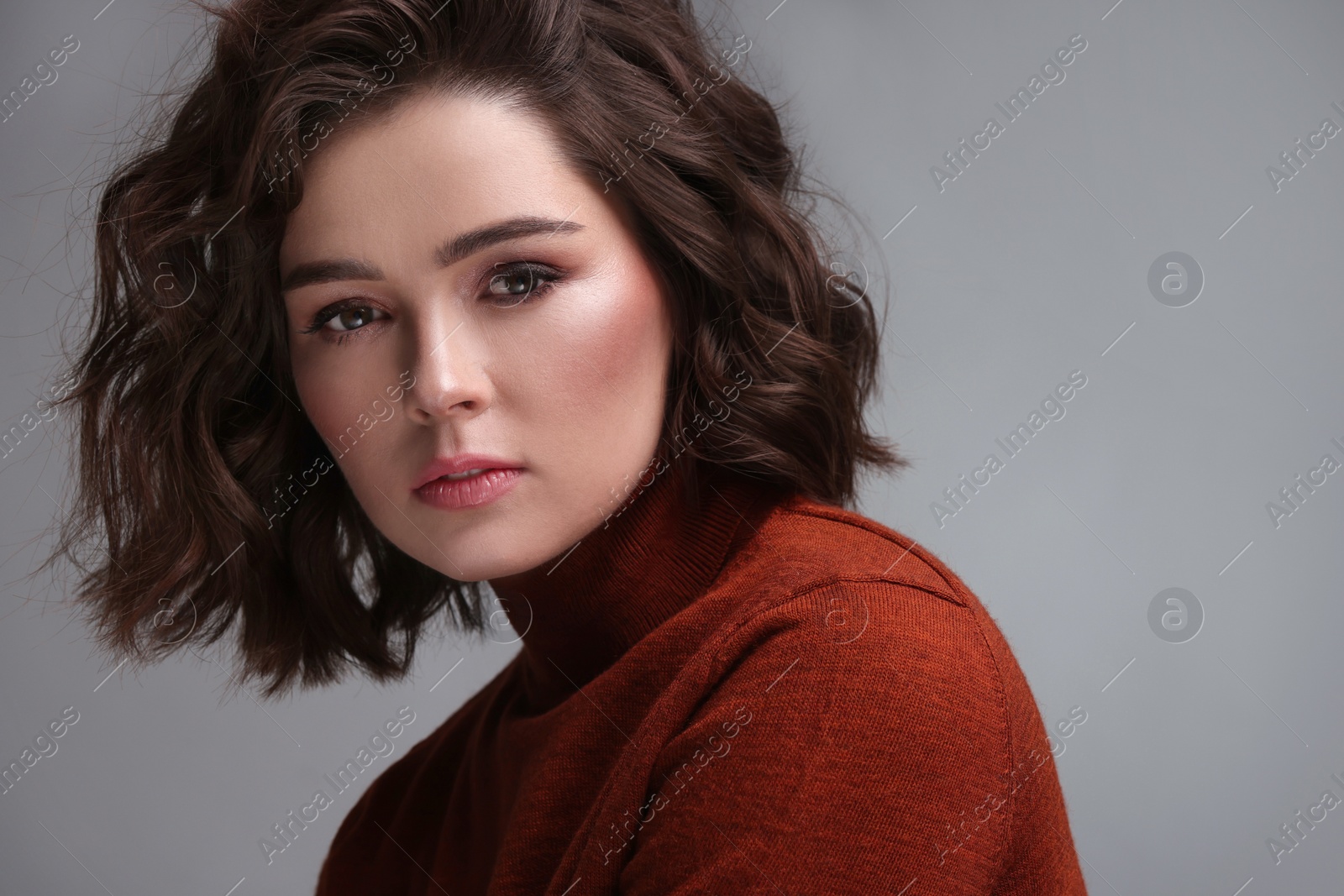 Photo of Beautiful young woman with wavy hairstyle on grey background