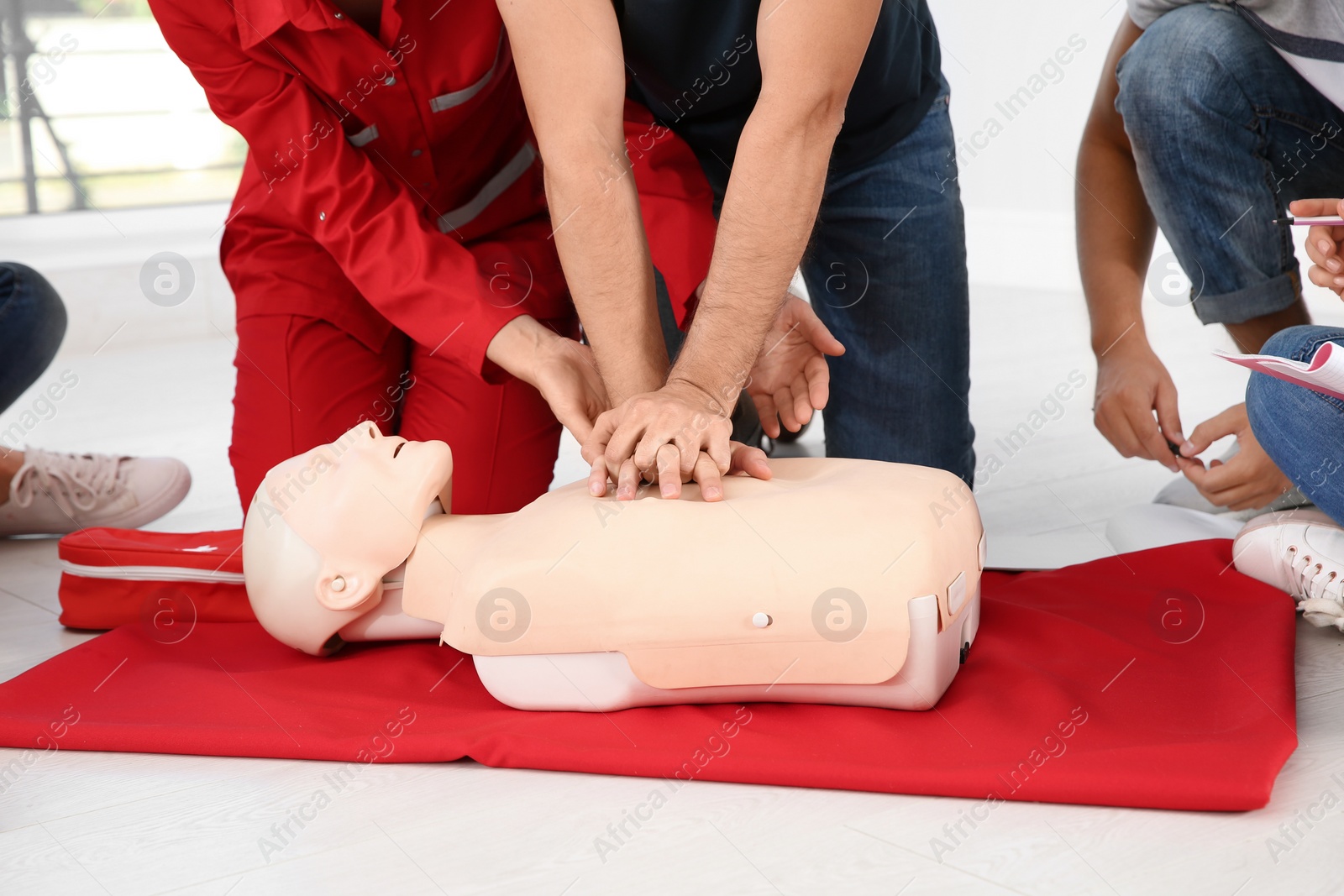 Photo of Group of people with instructor practicing CPR on mannequin at first aid class indoors, closeup