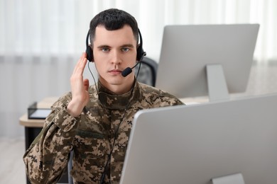 Photo of Military service. Young soldier in headphones working in office