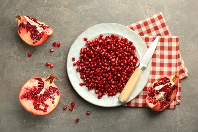 Photo of Tasty ripe pomegranate and grains on grey table, flat lay
