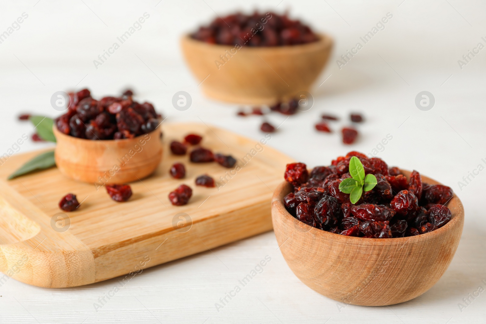 Photo of Tasty dried cranberries and leaves on white table. Space for text