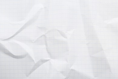 Crumpled checkered notebook sheet as background, top view