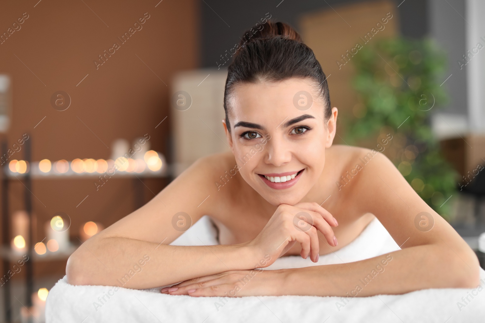 Photo of Young woman lying on massage table in spa salon