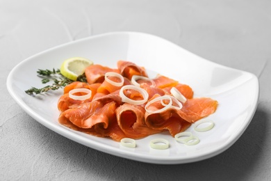 Photo of Plate with fresh sliced salmon fillet and onion on table