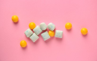 Different tasty chewing gums on pink background, flat lay