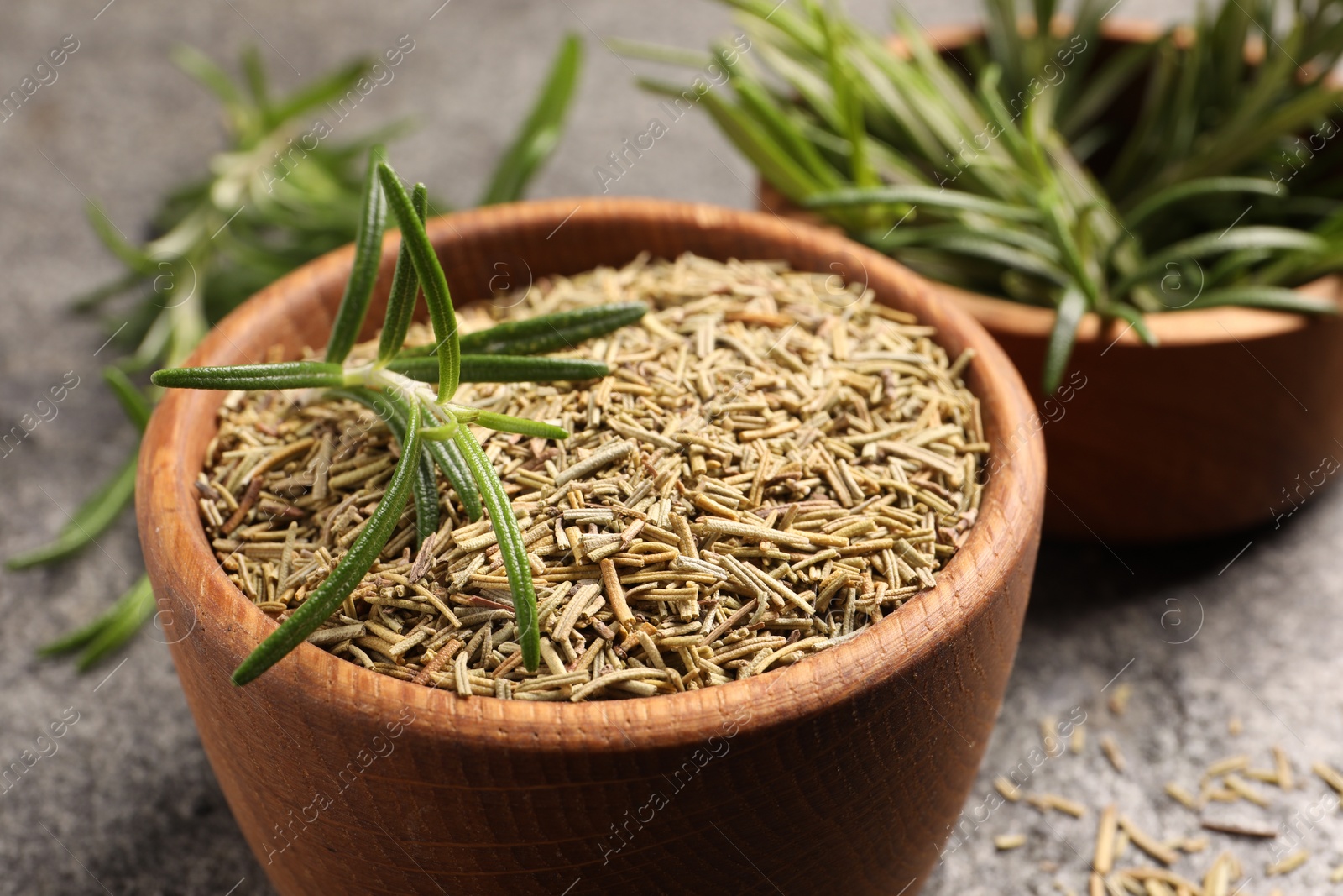 Photo of Bowl with dry and fresh rosemary on grey table, closeup