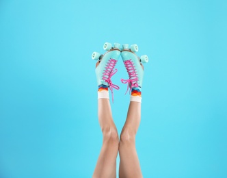 Young woman with retro roller skates on color background, closeup