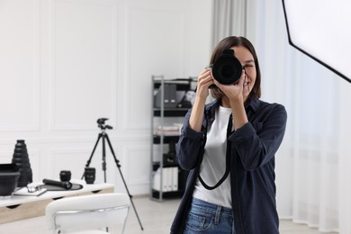 Photo of Young professional photographer taking picture in photo studio, space for text