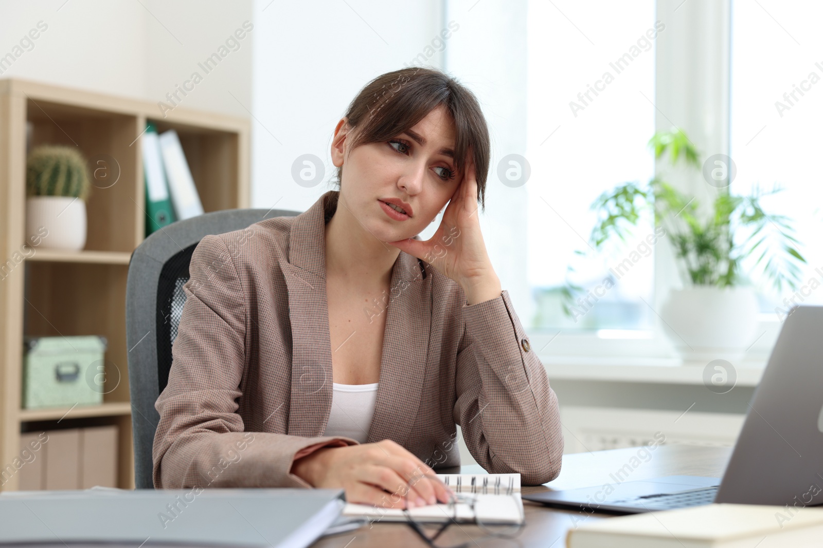 Photo of Overwhelmed office worker sitting at table with laptop indoors