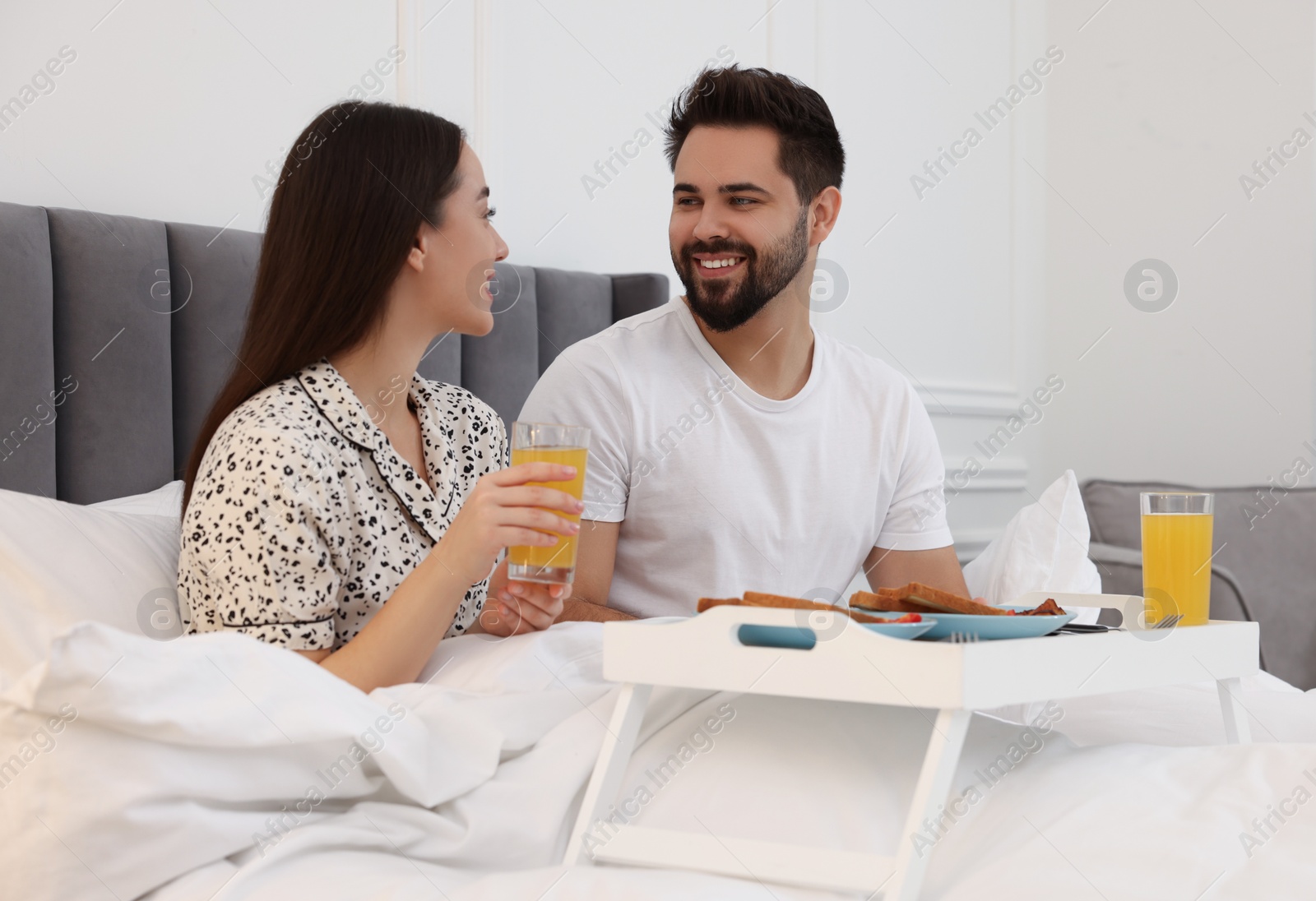 Photo of Happy couple having breakfast on bed at home