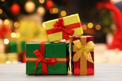 Photo of Beautiful gift boxes on wooden table against blurred festive lights. Christmas celebration