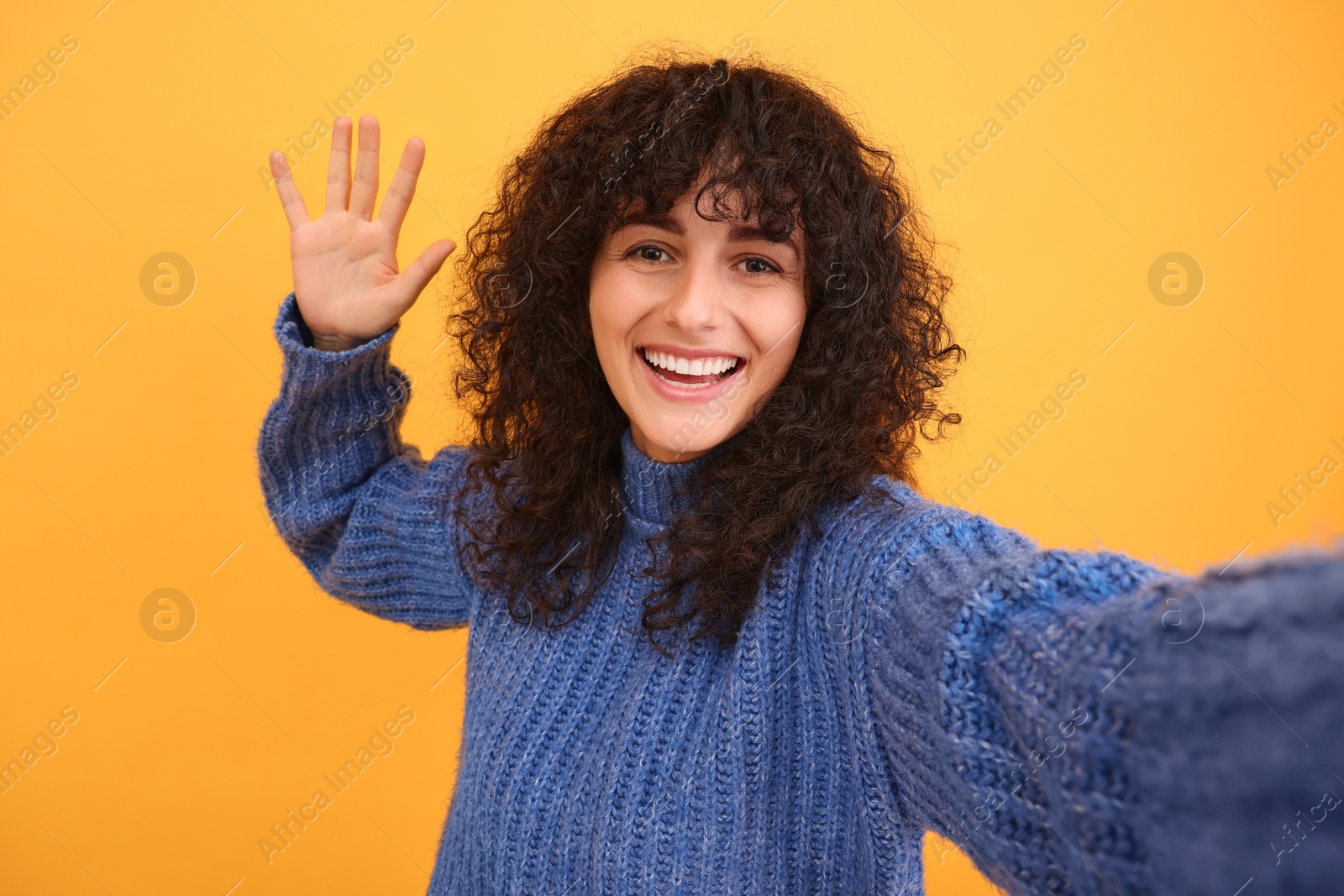 Photo of Beautiful young woman taking selfie on orange background