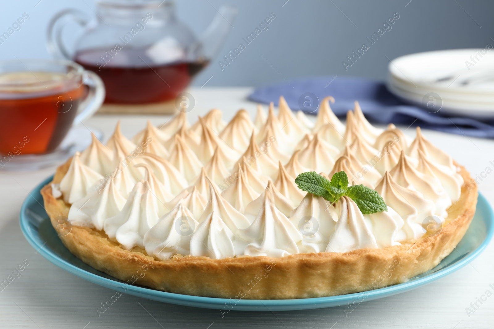 Photo of Delicious lemon meringue pie decorated with mint on white table