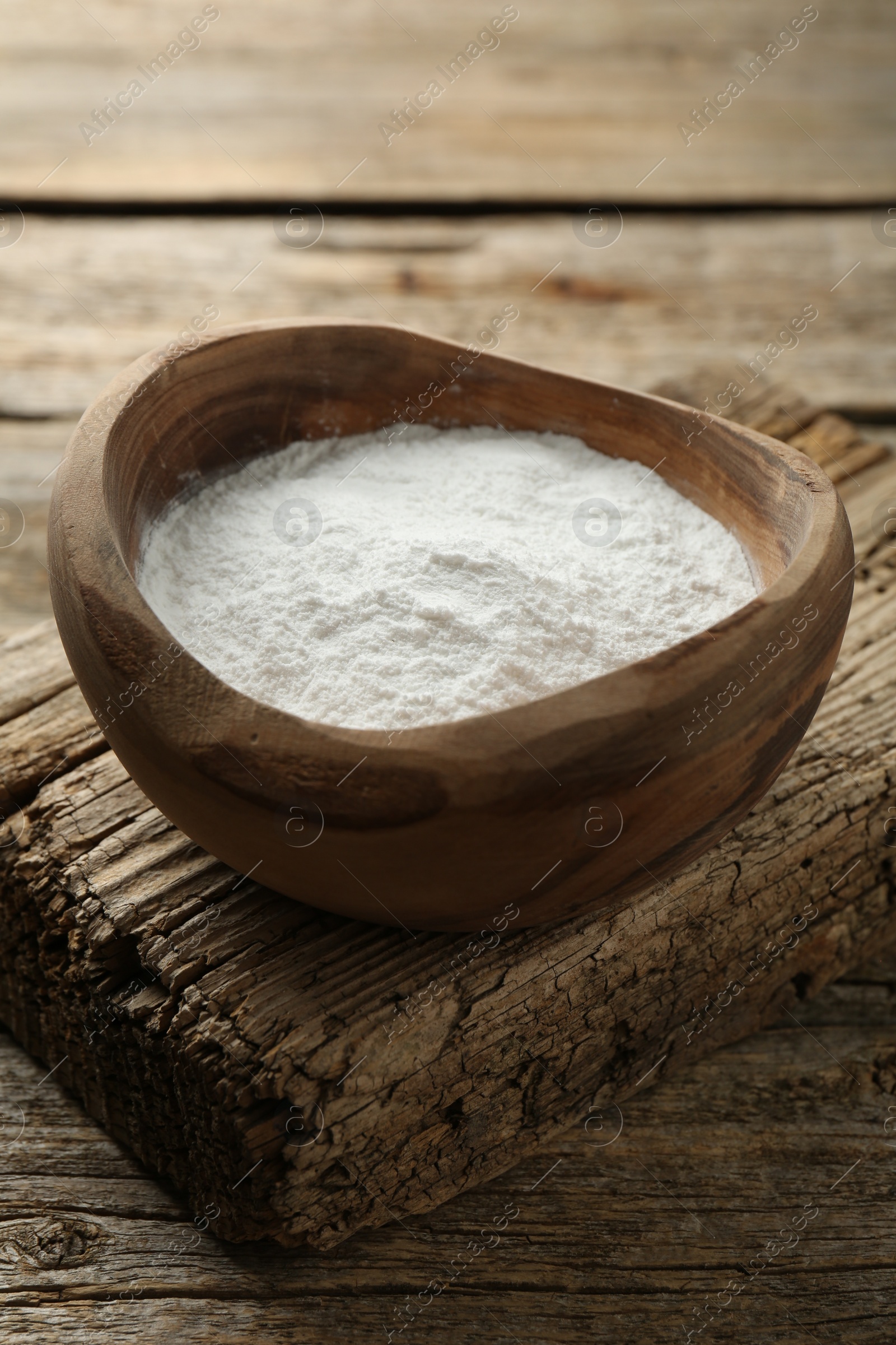 Photo of Baking powder in bowl on wooden table