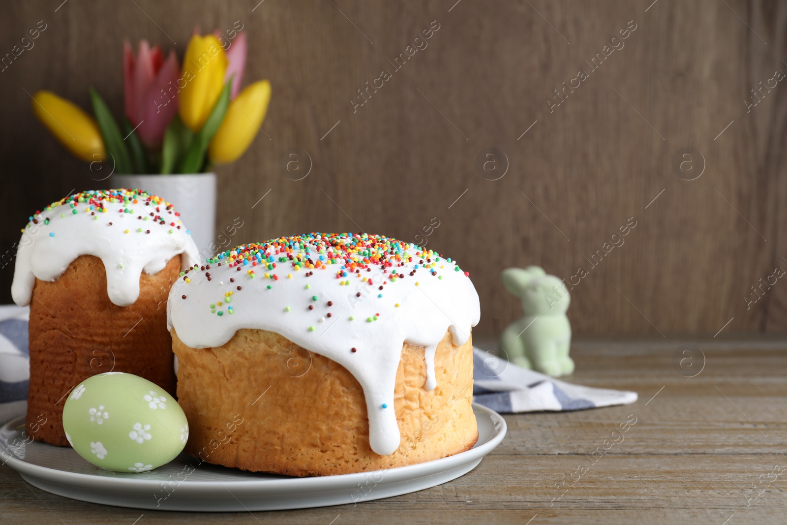 Photo of Easter cakes and color egg on wooden table, space for text