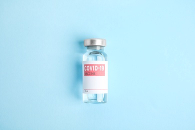 Vial with coronavirus vaccine on light blue background, top view
