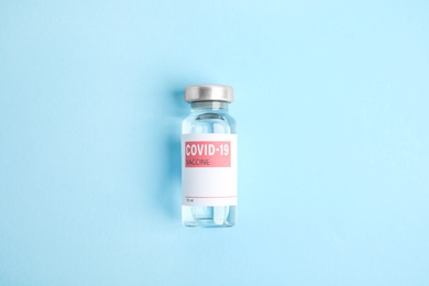 Photo of Vial with coronavirus vaccine on light blue background, top view