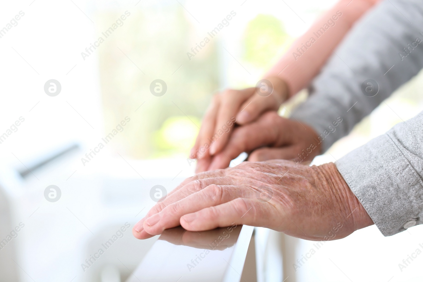 Photo of Helping hands on blurred background, closeup. Elderly care concept