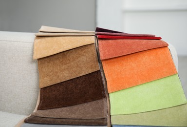 Photo of Catalog of colorful fabric samples on beige sofa, closeup