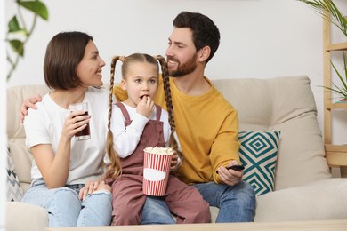 Photo of Happy family watching TV with popcorn on sofa indoors, space for text