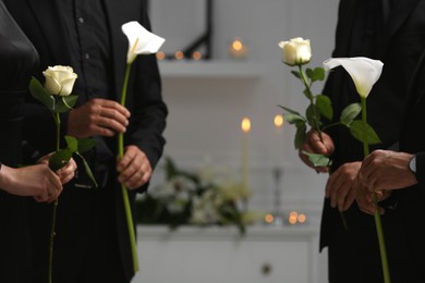 Photo of People with flowers indoors, closeup. Funeral ceremony