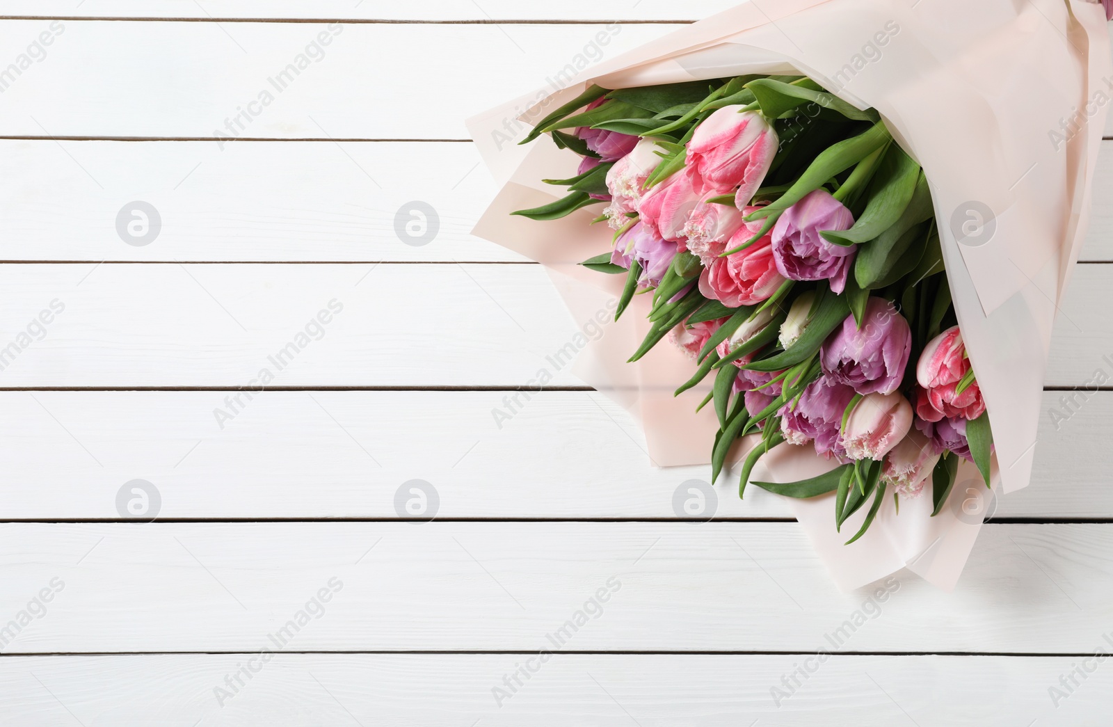 Photo of Bouquet of beautiful tulips on white wooden table, closeup. Space for text