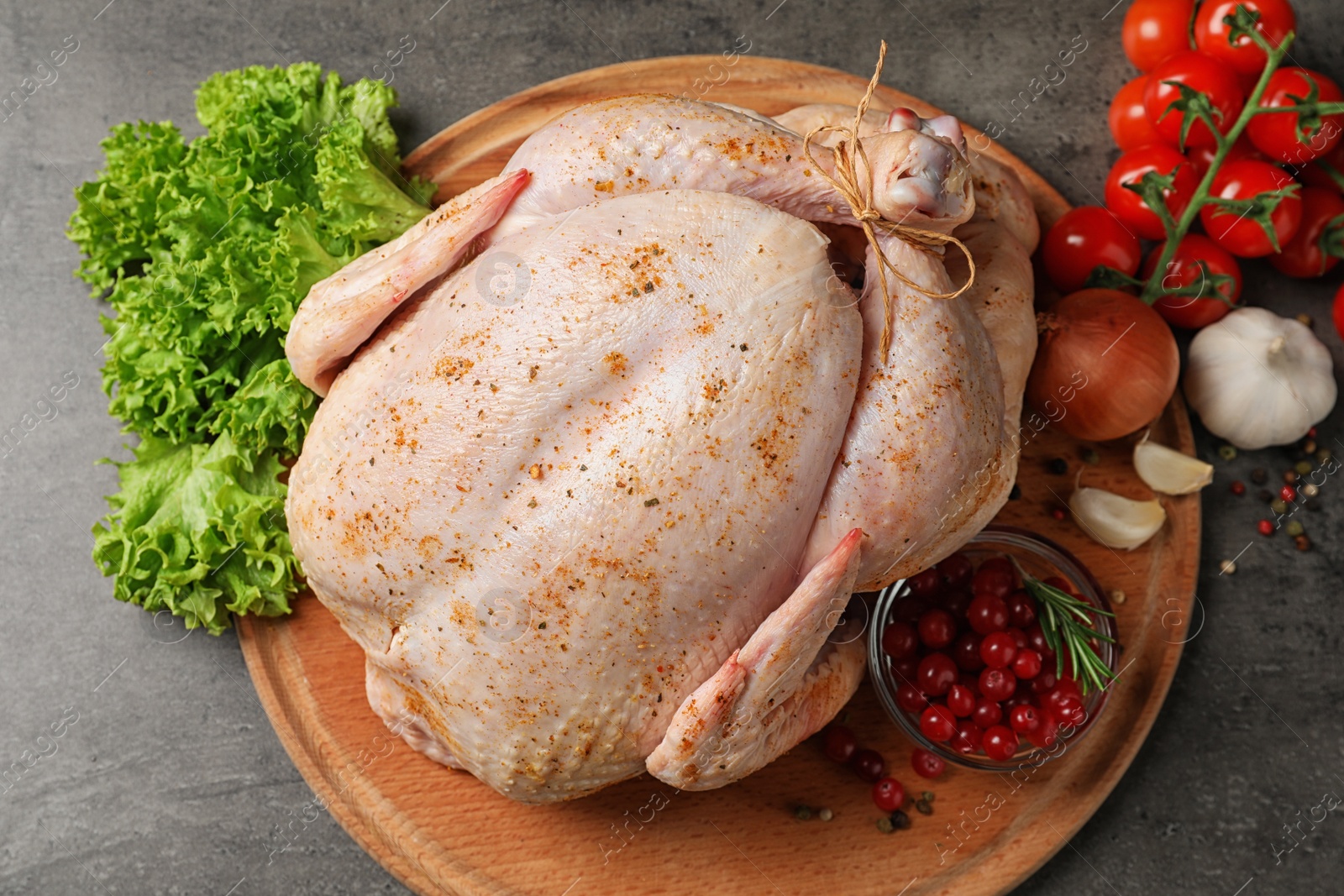 Photo of Wooden board with raw spiced turkey and ingredients on grey background, top view