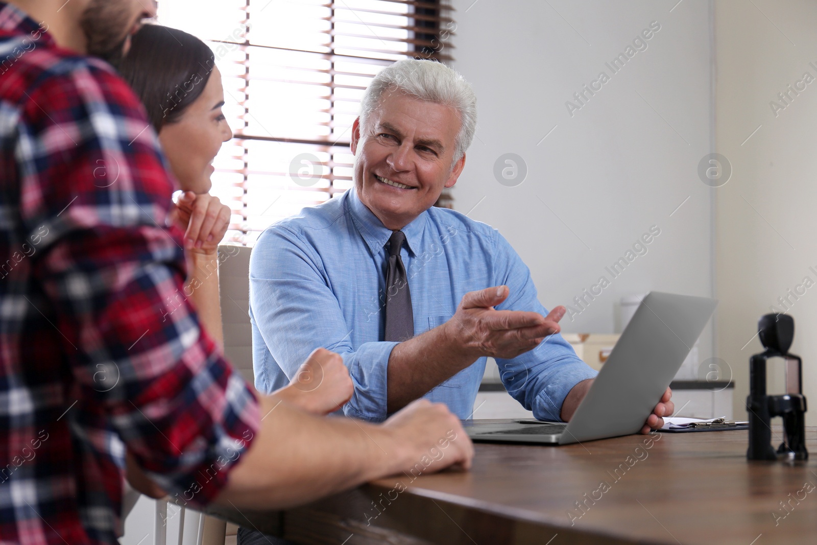 Photo of Senior notary working with young couple in office